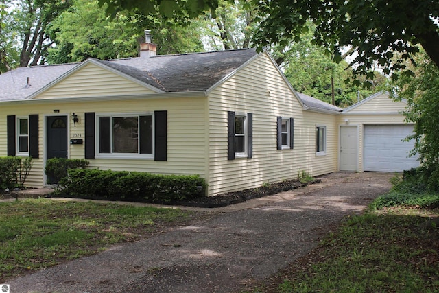 1023 S Elizabeth St, Mount Pleasant, MI 48858 - ranch-style home featuring asphalt driveway, a shingled roof, a chimney, and a garage