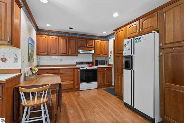906 Michigan Ave, Frankfort, MI 49635 - kitchen with white refrigerator with ice dispenser, electric stove, under cabinet range hood, stainless steel microwave, and brown cabinets