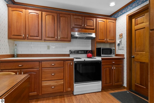 906 Michigan Ave, Frankfort, MI 49635 - kitchen featuring electric range oven, wallpapered walls, under cabinet range hood, stainless steel microwave, and light wood-style floors