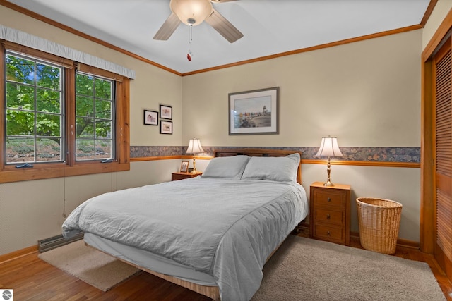906 Michigan Ave, Frankfort, MI 49635 - bedroom with a wainscoted wall, wood finished floors, crown molding, a closet, and ceiling fan