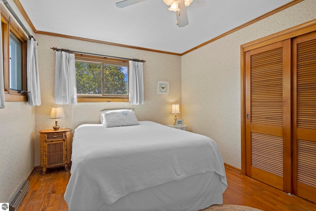 906 Michigan Ave, Frankfort, MI 49635 - bedroom featuring crown molding, a baseboard radiator, wood finished floors, a closet, and ceiling fan