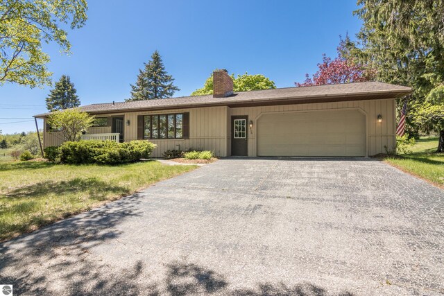 906 Michigan Ave, Frankfort, MI 49635 - ranch-style house with a chimney, an attached garage, asphalt driveway, and a front lawn