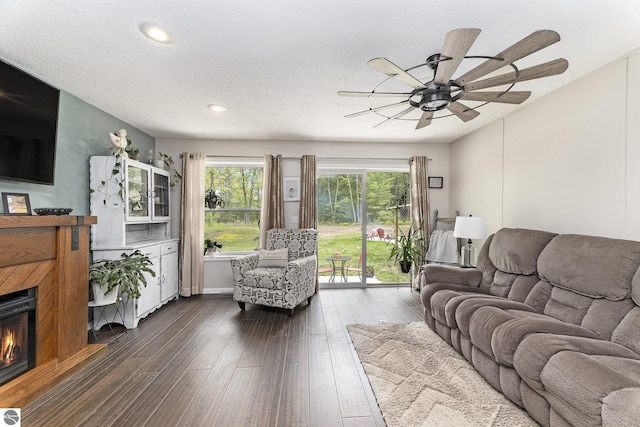 6313 E 34 1/2 Rd, Cadillac, MI 49601 - living area featuring ceiling fan, dark wood-style floors, recessed lighting, a warm lit fireplace, and a textured ceiling
