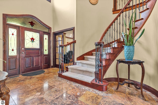 6853 S W Bay Shore Dr, Traverse City, MI 49684 - foyer entrance with baseboards, stone tile flooring, stairs, and a towering ceiling