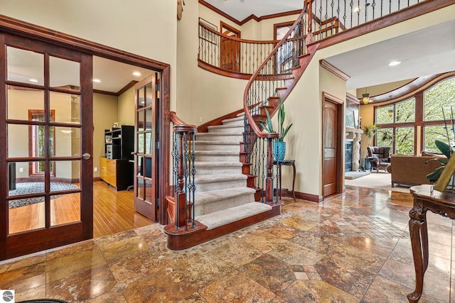 6853 S W Bay Shore Dr, Traverse City, MI 49684 - stairway with a high ceiling, baseboards, french doors, ornamental molding, and stone tile flooring