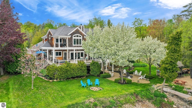 6853 S W Bay Shore Dr, Traverse City, MI 49684 - back of property featuring a fire pit, a wooden deck, a chimney, and a lawn