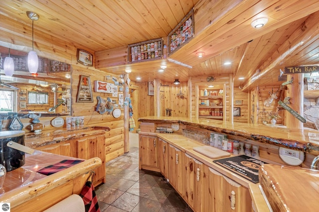6853 S W Bay Shore Dr, Traverse City, MI 49684 - kitchen with butcher block counters, stone tile flooring, wood ceiling, wooden walls, and hanging light fixtures
