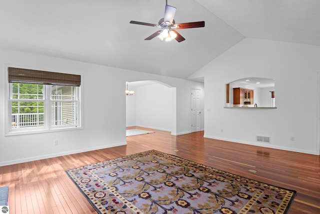 5151 Hidden Gables Dr, Traverse City, MI 49684 - unfurnished living room featuring ceiling fan, arched walkways, wood-type flooring, and high vaulted ceiling