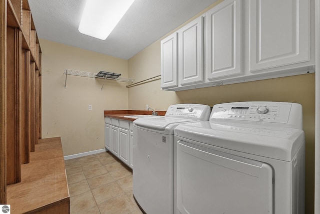 5151 Hidden Gables Dr, Traverse City, MI 49684 - laundry area with washing machine and clothes dryer, cabinet space, and light tile patterned floors