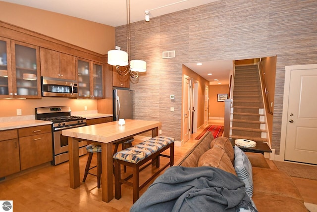 4365 W Burdickville Rd, Maple City, MI 49664 - kitchen featuring appliances with stainless steel finishes, brown cabinets, light countertops, pendant lighting, and glass insert cabinets