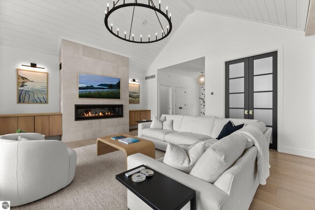6848 S Carol Ann Dr, Traverse City, MI 49684 - living area with wood finished floors, wooden ceiling, a tile fireplace, a chandelier, and high vaulted ceiling