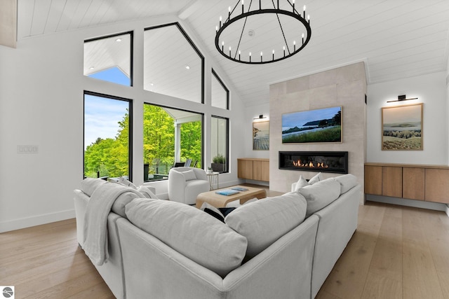 6848 S Carol Ann Dr, Traverse City, MI 49684 - living room with high vaulted ceiling, wood finished floors, a fireplace, a chandelier, and baseboards