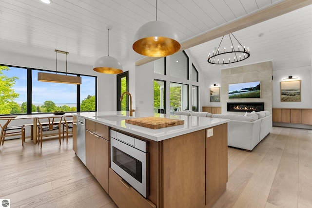 6848 S Carol Ann Dr, Traverse City, MI 49684 - kitchen featuring a sink, light wood-style flooring, stainless steel appliances, an island with sink, and wood ceiling