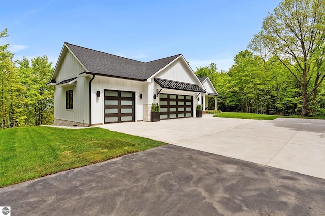 6848 S Carol Ann Dr, Traverse City, MI 49684 - view of side of property featuring a garage, concrete driveway, a yard, a shingled roof, and board and batten siding