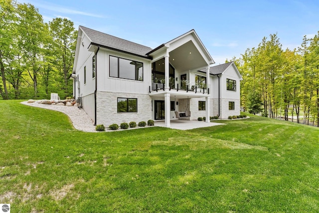 6848 S Carol Ann Dr, Traverse City, MI 49684 - back of house featuring a balcony, a patio area, a yard, and stone siding