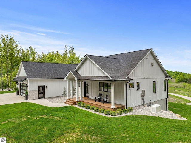 6848 S Carol Ann Dr, Traverse City, MI 49684 - back of house with roof with shingles, a porch, a lawn, and concrete driveway