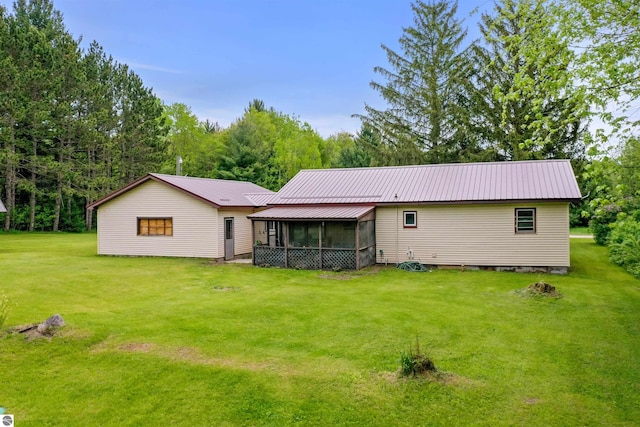 6148 S 27th Rd, Cadillac, MI 49601 - back of property with a sunroom, a lawn, and metal roof