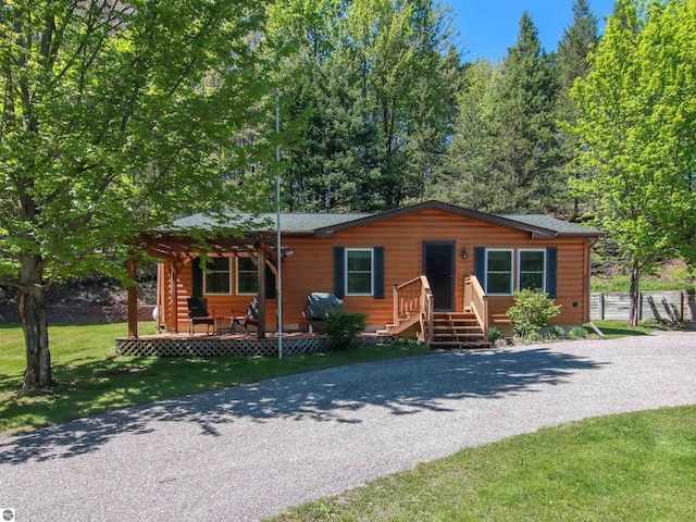 8086 Narrow Gauge Rd, Beulah, MI 49617 - view of front of property featuring a pergola, gravel driveway, a front yard, and faux log siding