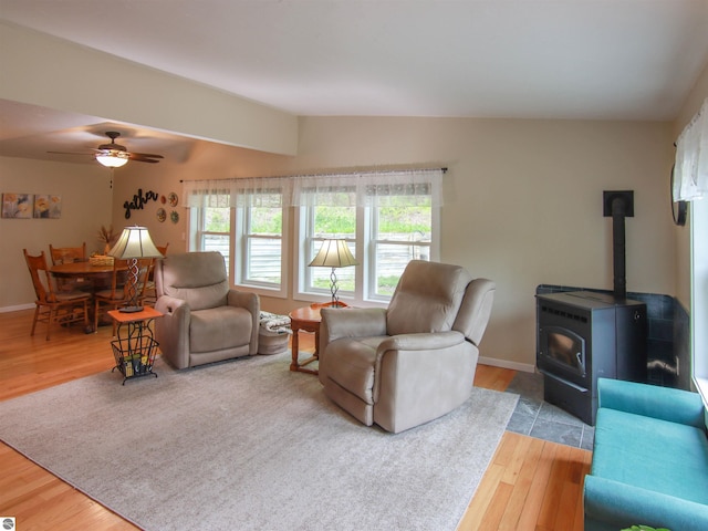 8086 Narrow Gauge Rd, Beulah, MI 49617 - living room featuring vaulted ceiling, a wood stove, wood finished floors, ceiling fan, and baseboards