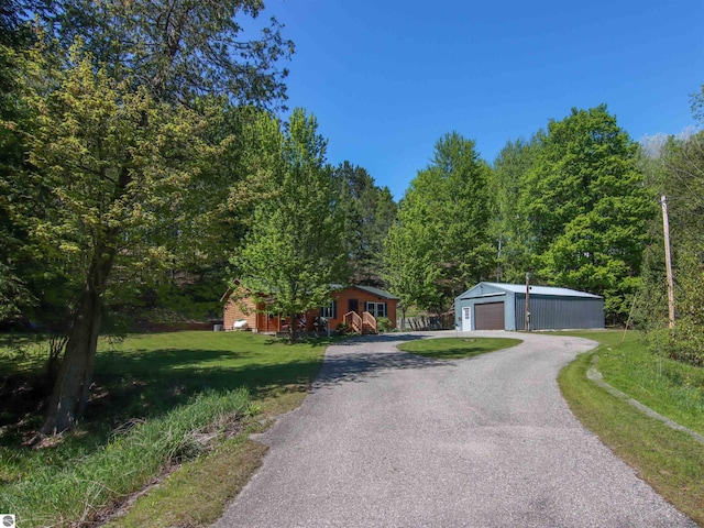 8086 Narrow Gauge Rd, Beulah, MI 49617 - view of property hidden behind natural elements featuring a detached garage, an outbuilding, a front lawn, driveway, and a forest view