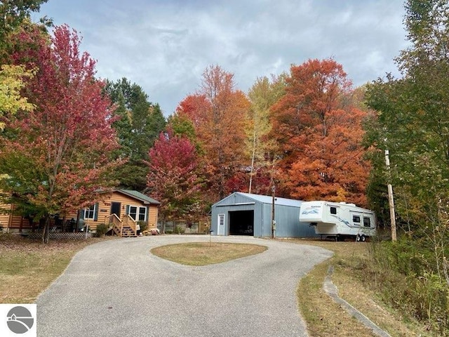 8086 Narrow Gauge Rd, Beulah, MI 49617 - view of front of home featuring a garage, an outbuilding, and asphalt driveway