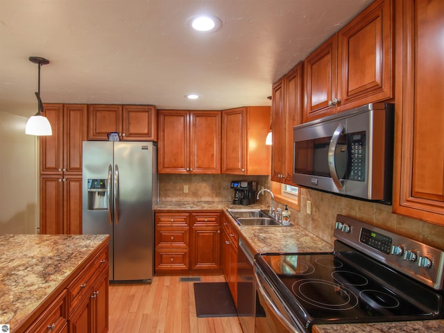 8086 Narrow Gauge Rd, Beulah, MI 49617 - kitchen featuring stainless steel appliances, a sink, brown cabinets, light wood finished floors, and backsplash
