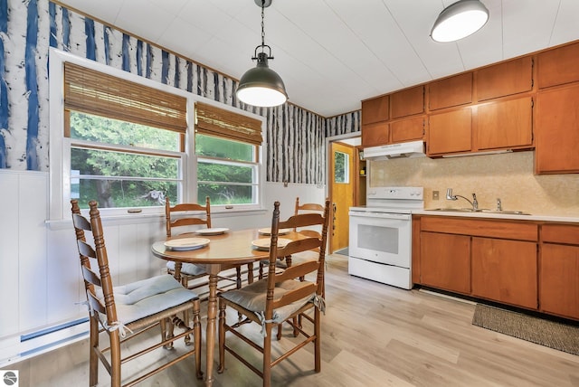 7510 Crystal Dr, Beulah, MI 49616 - kitchen with white electric range, wallpapered walls, under cabinet range hood, a sink, and a wainscoted wall