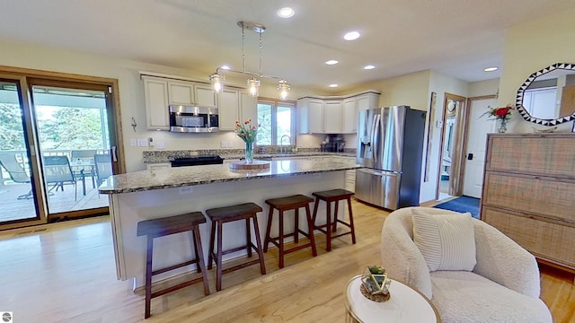 2152 Cornerstone Dr, Mount Pleasant, MI 48858 - kitchen featuring appliances with stainless steel finishes, a center island, stone counters, a breakfast bar area, and recessed lighting