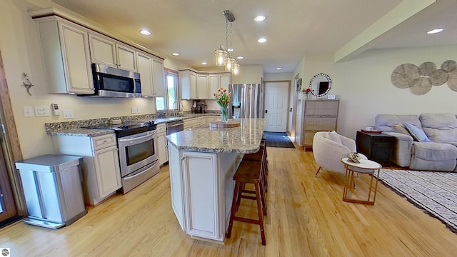 2152 Cornerstone Dr, Mount Pleasant, MI 48858 - kitchen with stainless steel appliances, open floor plan, a kitchen breakfast bar, light wood-type flooring, and light stone countertops