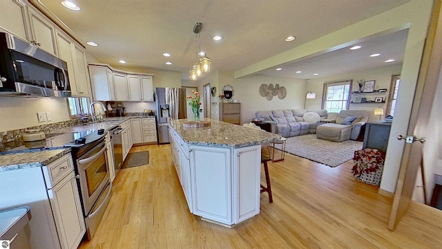2152 Cornerstone Dr, Mount Pleasant, MI 48858 - kitchen with stainless steel appliances, light wood-style flooring, a sink, a kitchen island, and open floor plan