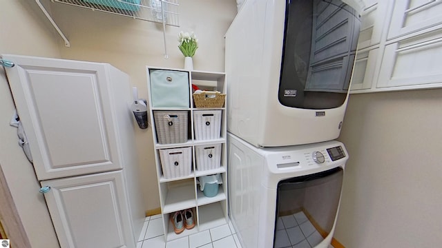 2152 Cornerstone Dr, Mount Pleasant, MI 48858 - laundry room featuring stacked washer and clothes dryer, tile patterned floors, cabinet space, and baseboards