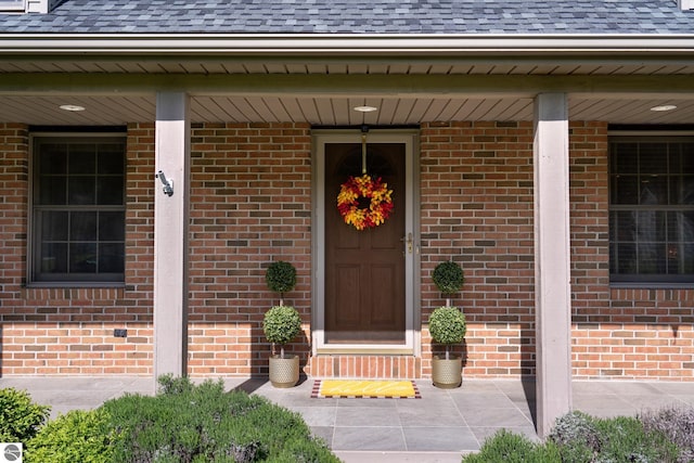 2152 Cornerstone Dr, Mount Pleasant, MI 48858 - doorway to property featuring a porch, roof with shingles, and brick siding