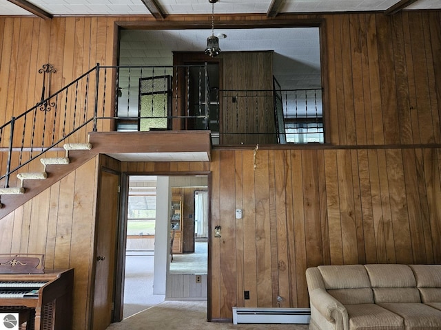 4451 Bissonette Rd, Oscoda, MI 48750 - carpeted living area with a baseboard heating unit, wooden walls, stairway, and beam ceiling