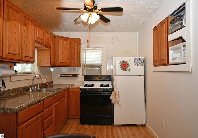 4327 S M-65, Glennie, MI 48737 - kitchen with range with gas stovetop, freestanding refrigerator, a sink, light wood-style flooring, and brown cabinetry