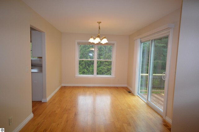 1433 Elk Run, Traverse City, MI 49696 - unfurnished dining area featuring a chandelier, light wood-style floors, and baseboards