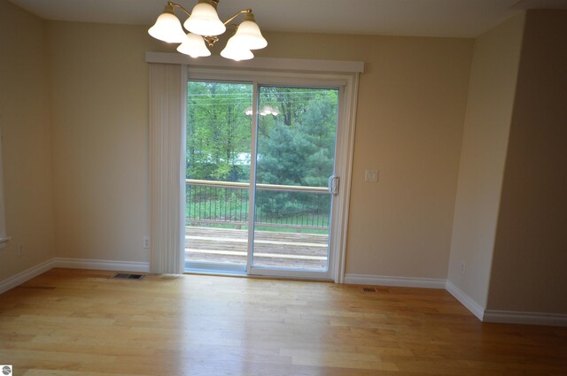 1433 Elk Run, Traverse City, MI 49696 - unfurnished room with a chandelier, wood finished floors, and baseboards
