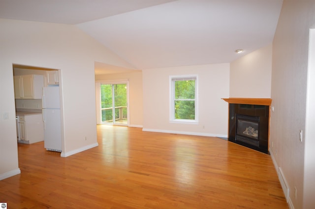 1433 Elk Run, Traverse City, MI 49696 - unfurnished living room featuring light wood-style floors, a fireplace, baseboards, and lofted ceiling