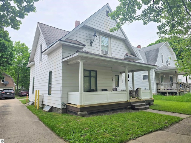 820 Wallace St, Cadillac, MI 49601 - view of front of home featuring a porch, a chimney, and a front lawn