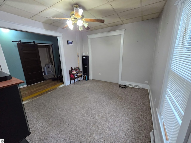 820 Wallace St, Cadillac, MI 49601 - unfurnished room featuring a barn door, ceiling fan, carpet floors, and a paneled ceiling