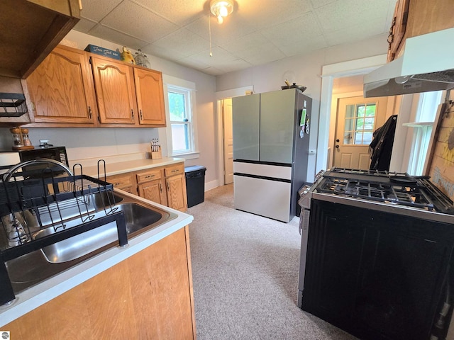 820 Wallace St, Cadillac, MI 49601 - kitchen featuring gas range oven, freestanding refrigerator, light carpet, under cabinet range hood, and light countertops
