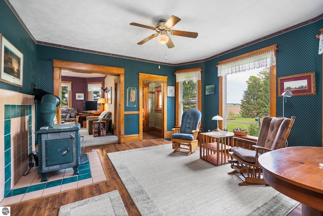 9889 Ramsay Rd, Buckley, MI 49620 - living area featuring a wood stove, wallpapered walls, a ceiling fan, wood finished floors, and crown molding
