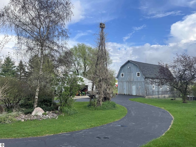 9889 Ramsay Rd, Buckley, MI 49620 - view of side of home with a barn, a gambrel roof, an outdoor structure, curved driveway, and a yard