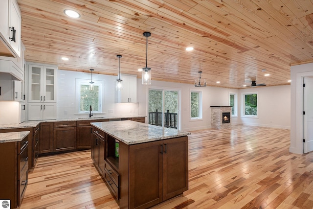 4144 S Sugar Loaf Mountain Rd, Cedar, MI 49621 - kitchen with wood ceiling, light wood-style floors, a center island, white cabinets, and open shelves