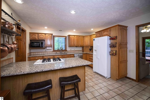10226 Deerpath N, Traverse City, MI 49685 - kitchen with white appliances, a sink, a kitchen breakfast bar, brown cabinets, and recessed lighting