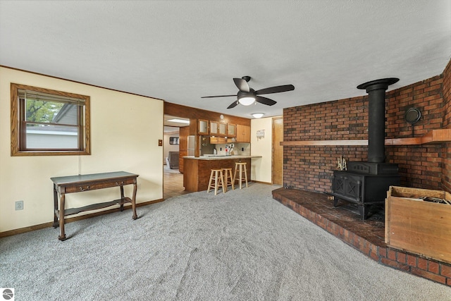 217 Winona Pl, Cadillac, MI 49601 - living area with a wood stove, carpet floors, ceiling fan, a textured ceiling, and baseboards