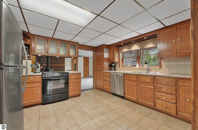 217 Winona Pl, Cadillac, MI 49601 - kitchen with appliances with stainless steel finishes, a sink, brown cabinets, a drop ceiling, and decorative backsplash