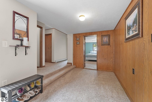 217 Winona Pl, Cadillac, MI 49601 - corridor featuring a baseboard heating unit, wood walls, carpet, and baseboards