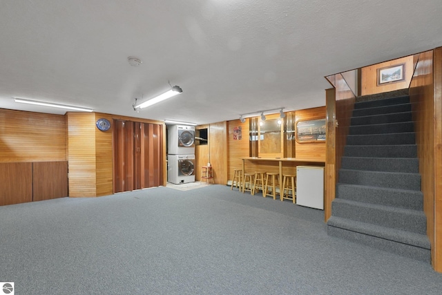 217 Winona Pl, Cadillac, MI 49601 - finished below grade area featuring stacked washer / dryer, stairway, wood walls, carpet, and a dry bar
