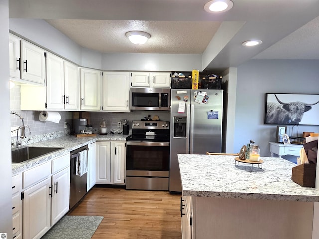 902 S Crapo St, Mount Pleasant, MI 48858 - kitchen with appliances with stainless steel finishes, a sink, white cabinetry, light wood-style flooring, and recessed lighting