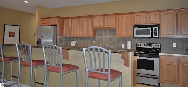 1491 Kent St Unit 9, Traverse City, MI 49686 - kitchen with stainless steel appliances, decorative backsplash, a breakfast bar area, a center island, and recessed lighting
